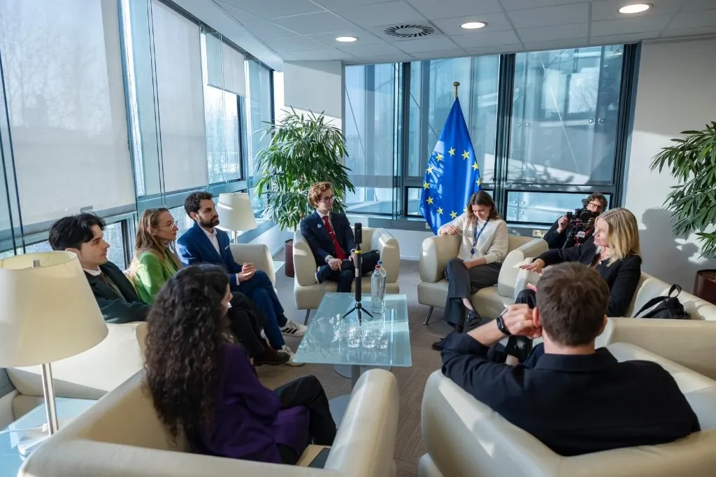 Young professionals and partners in discussion at a modern office with a European Union flag in the background